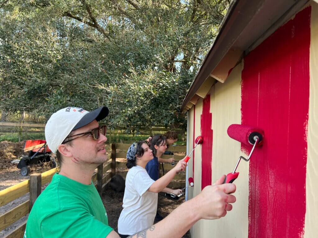 People Painting A Barn Red