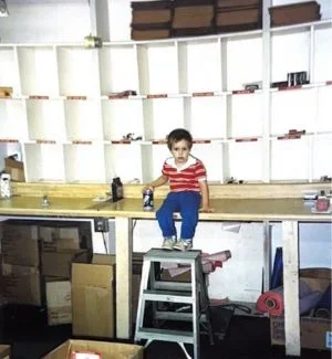 Jesse as a little kid sitting on the stamp assembly work bench